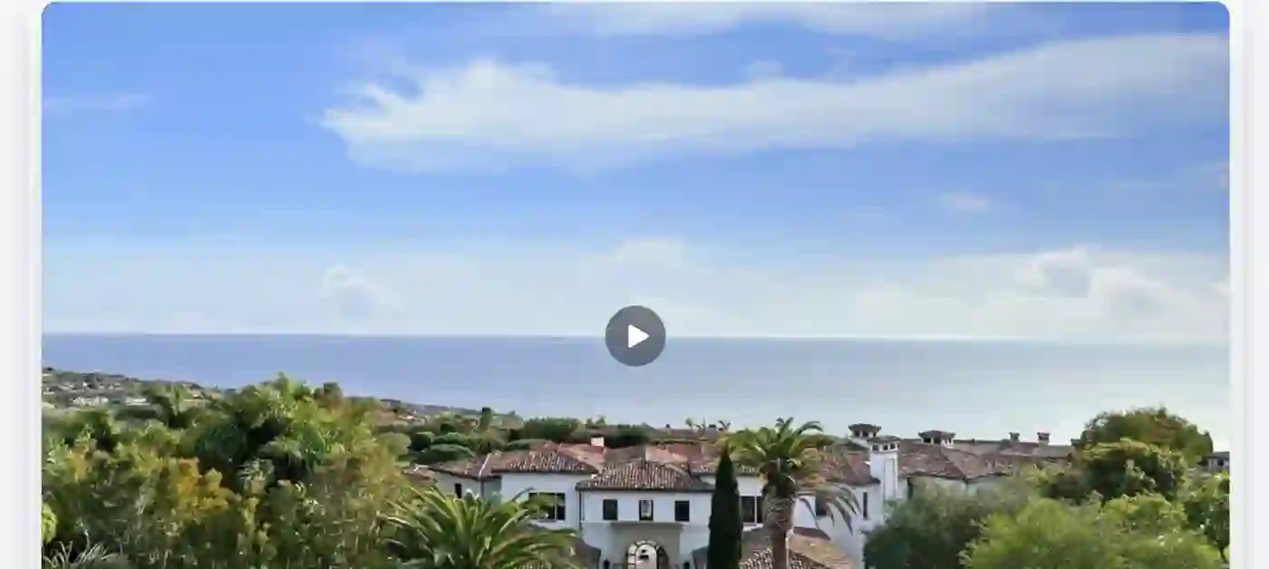 A drop-in video widget showing an ocean-view estate with an inline play button.